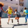 Elèves de dos courant devant leur école